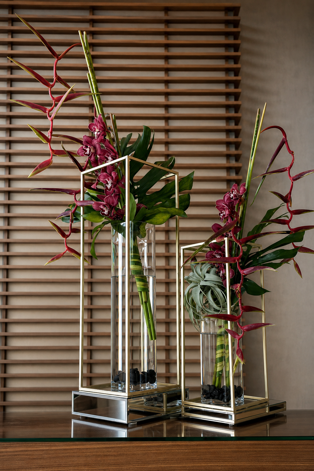 Sculptural burgundy orchids in polished brass and glass vessels